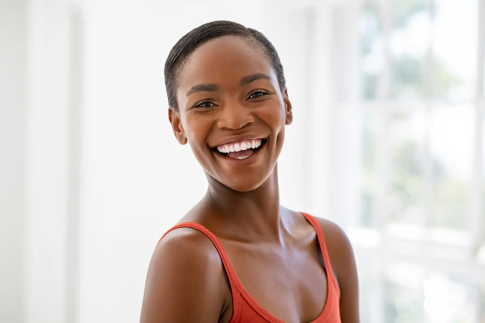 Smiling woman with short hair wearing a red tank top.